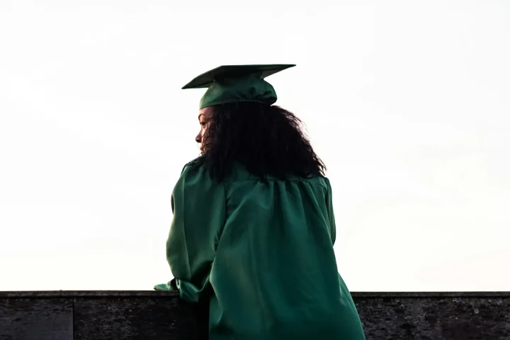 Graduate in a green gown looking out over the city